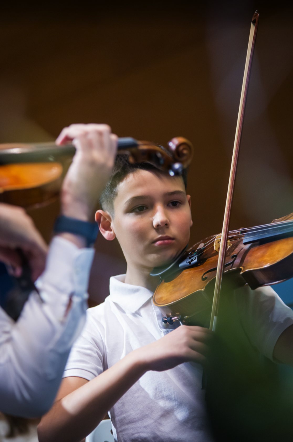 Jovem violinista da Camerata Virtuosa, concentrado, a tocar em concerto
